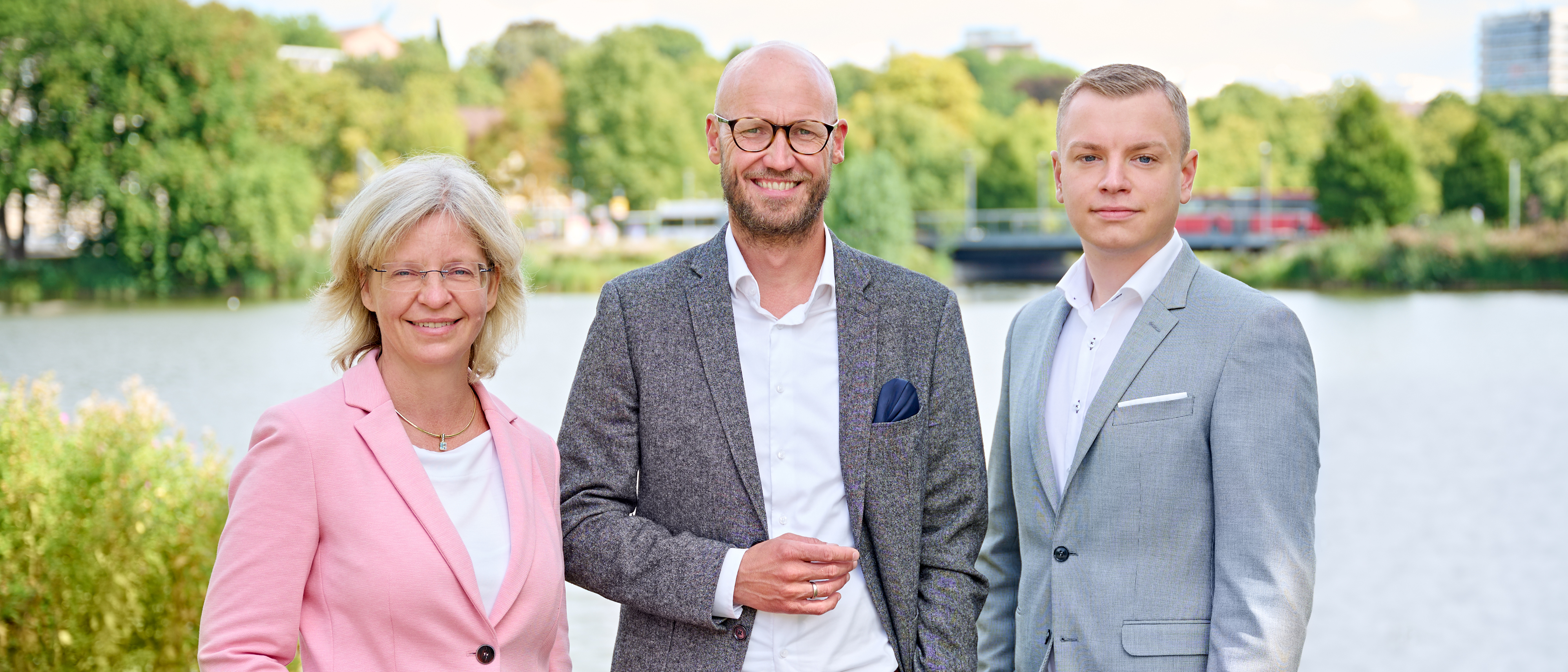 Frau Zauka, Herr Wohlert und Herr Paul stehen nebeneinander und blicken lächelnd in die Kamera.
